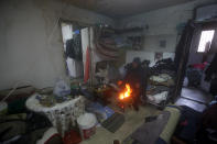 A man warms himself around a fire inside his rooftop room, in the southern port city of Sidon, Lebanon, Wednesday, Jan. 19, 2022. A snowstorm in the Middle East has left many Lebanese and Syrians scrambling to find ways to survive. Some are burning old clothes, plastic and other hazardous materials to keep warm as temperatures plummet and poverty soars. (AP Photo/Mohammed Zaatari)