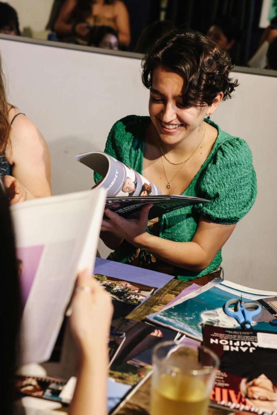 A seated woman flips through a magazine