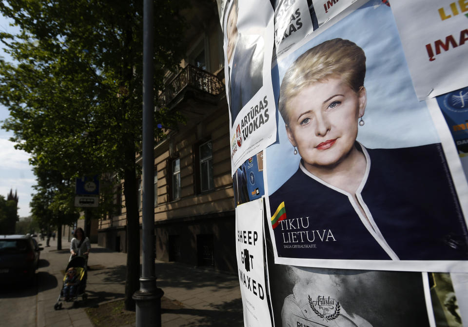 A local resident walks by an election poster showing Lithuania's President Dalia Grybauskaite, a presidential candidate, installed in Vilnius, Lithuania, Friday, May 9, 2014. The poster reads " I believe in Lithuania" . Lithuanians will ballot Sunday, May 11, in a first round of presidential elections. (AP Photo/Mindaugas Kulbis)