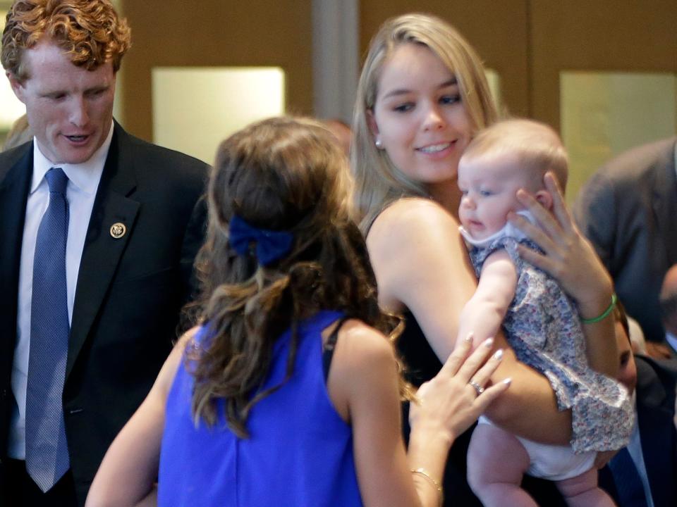 Saoirse Kennedy Hill holds a relative's baby alongside Joseph Kennedy III.