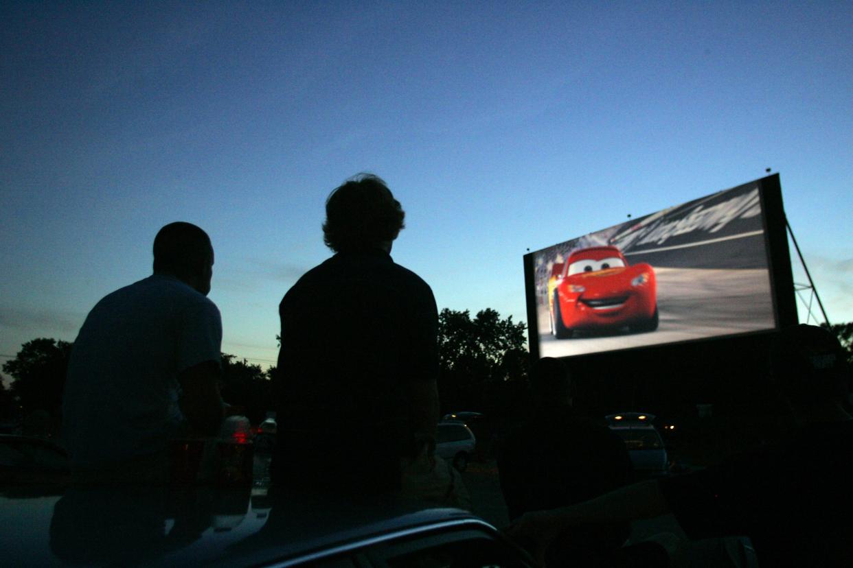 In this 2006 photo, Jon Martin and Keith Sorgius sit atop their vehicle as they watch the movie, "Cars," at the Tibbs Drive-In on June 16, 2006.