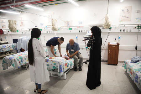 An Israeli doctor treats a Syrian baby who, together with other Syrians, crossed the armistice line from Syria to the Israeli-occupied Golan Heights to get medical treatment in Israel, July 11, 2018. REUTERS/ Ronen Zvulun