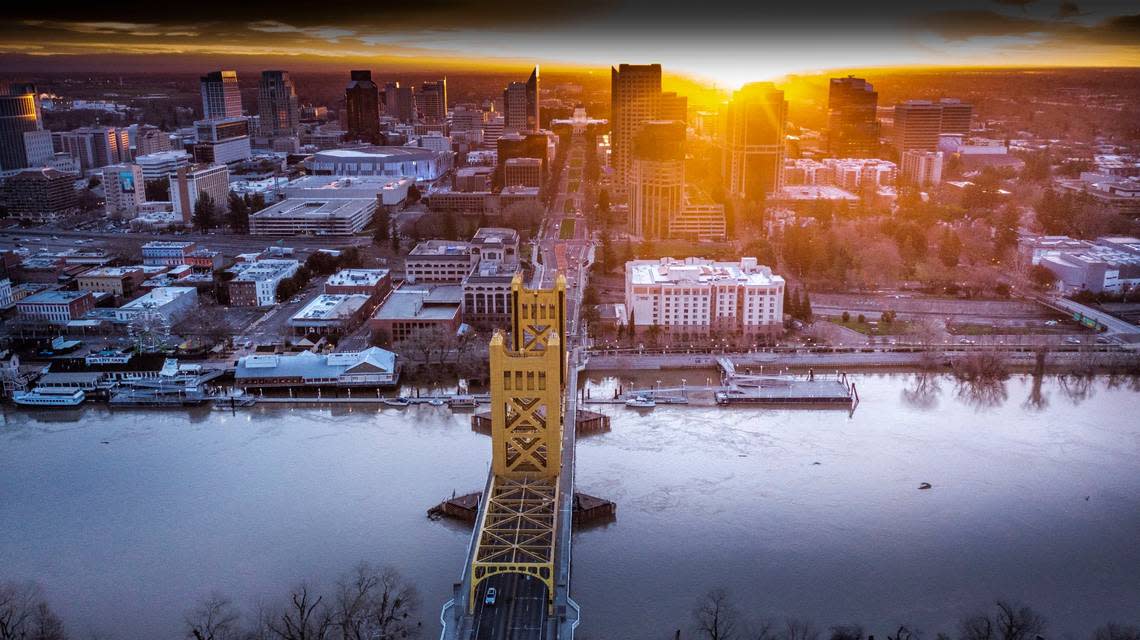 The sun rises over Sacramento and a swollen Sacramento River in a drone photo on Thursday, Jan. 12, 2023.