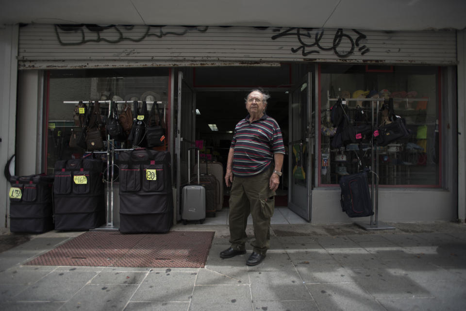 Luggage seller Jose Forteza, 88, poses for a portrait outside his store, one of the few still open in the Paseo de Diego of San Juan, Puerto Rico, Wednesday, April 17, 2019. Paseo de Diego, the central thoroughfare in Rio Piedras, was filled years ago with stores that are closed and empty today. (AP Photo/Carlos Giusti)
