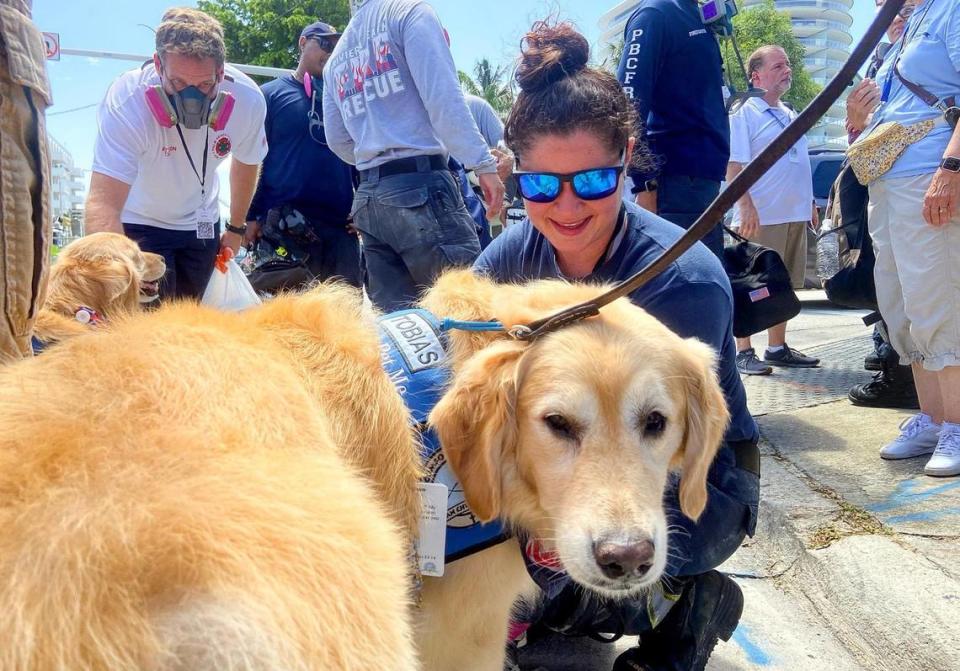 Delray Beach Firefighter Cecilia Abaldo pets Tobias, a comfort dog from the Lutheran Church Charities, as she finishes her shift working in the rubble of the Champlain Towers South collapse on Thursday, July 8, 2021. The focus has shifted to search and recovery at the site in Surfside.