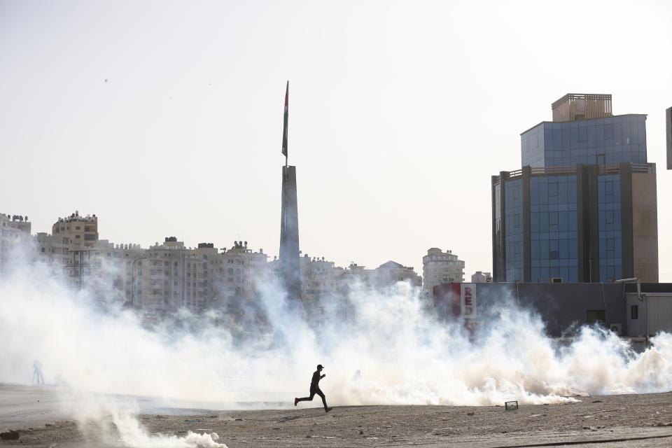 Palestinian demonstrators run from tear gas fired by Israeli troops during the protest against the U.S. announcement that it no longer believes Israeli settlements violate international law., at checkpoint Beit El near the West Bank city of Ramallah, Tuesday, Nov. 26, 2019, (AP Photo/Majdi Mohammed)