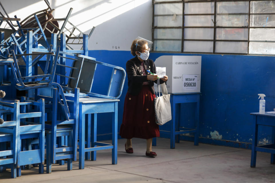 A woman wearing a mask to curb the spread of the new coronavirus carries her marked ballot during general elections at the Villa El Salvador neighborhood in Lima, Peru, Sunday, April 11, 2021. (AP Photo/Guadalupe Pardo)