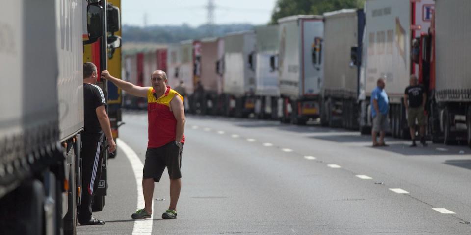 Drivers wait next to their parked lorries on the M20 motorway, which leads from London to the Channel Tunnel terminal at Ashford and the Ferry Terminal at Dover, as part of Operation Stack in southern England, Britain July 31, 2015.