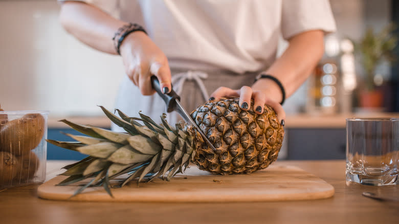 person cutting pineapple