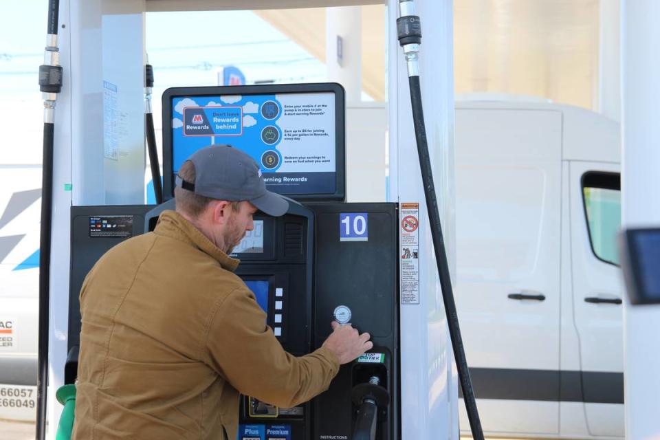 Kentucky Agriculture Commissioner Jonathan Shell places a “never leave children or pets in a hot vehicle” sticker on a gas pump.