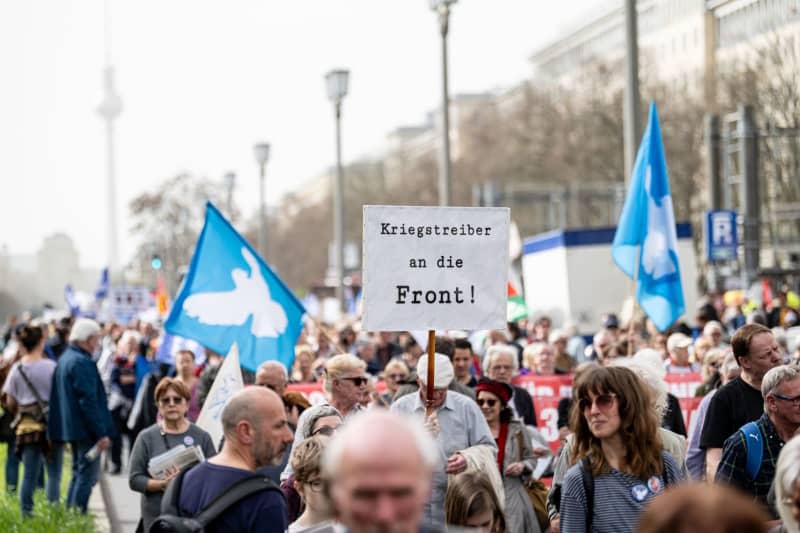 People with a banner reading "Warmongers to the front" take part in the traditional Easter march under the slogan "Warlike - Never Again". Fabian Sommer/dpa