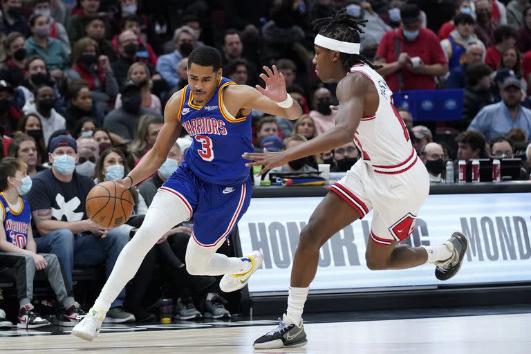 Jordan Poole, izquierda, de los Warriors de Golden State, conduce el balón en contra de Ayo Dosunmu, de los Bulls de Chicago, durante la primera mitad del juego de la NBA en Chicago, el viernes 14 de enero de 2022. (AP Foto/Nam Y. Huh)