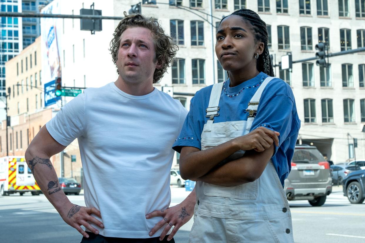 jeremy allen white and ayo edebiri in the bear, standing with puzzled expressions on their faces on a street