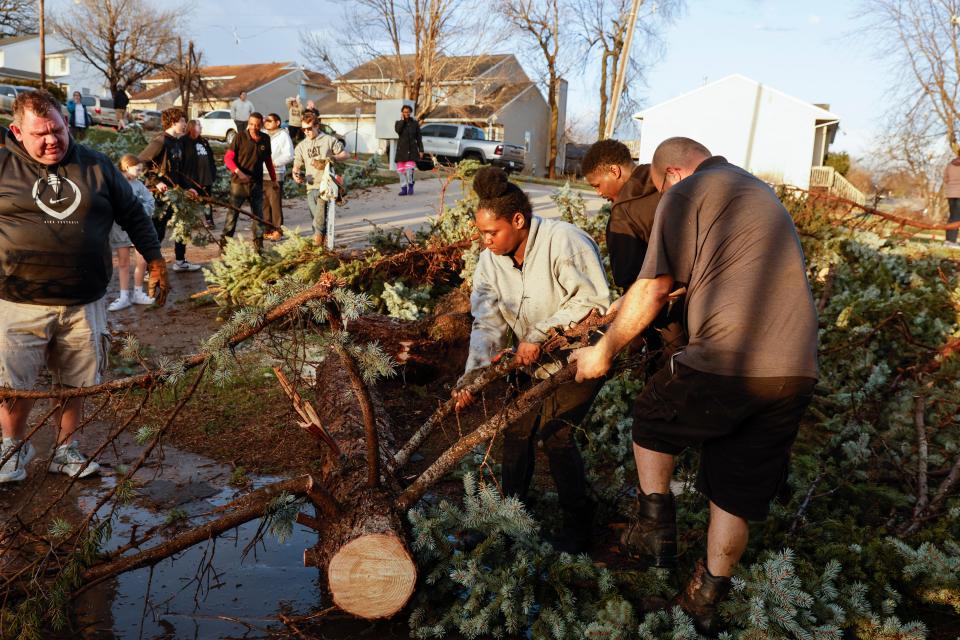 Coriana Moore, 17, pitches in to clean up after a tornado touched down near the intersection of 23rd Avenue and Ninth Street in Coralville, Iowa, Friday, March 31, 2023. City crews, residents and neighbors worked to clear debris off the roadway and vehicles. (Jim Slosiarek/The Gazette via AP)