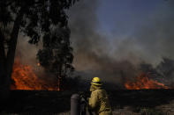 A firefighter watches flames from the Silverado Fire, Monday, Oct. 26, 2020, in Irvine, Calif. A fast-moving wildfire forced evacuation orders for 60,000 people in Southern California on Monday as powerful winds across the state prompted power to be cut to hundreds of thousands to prevent utility equipment from sparking new blazes. (AP Photo/Jae C. Hong)