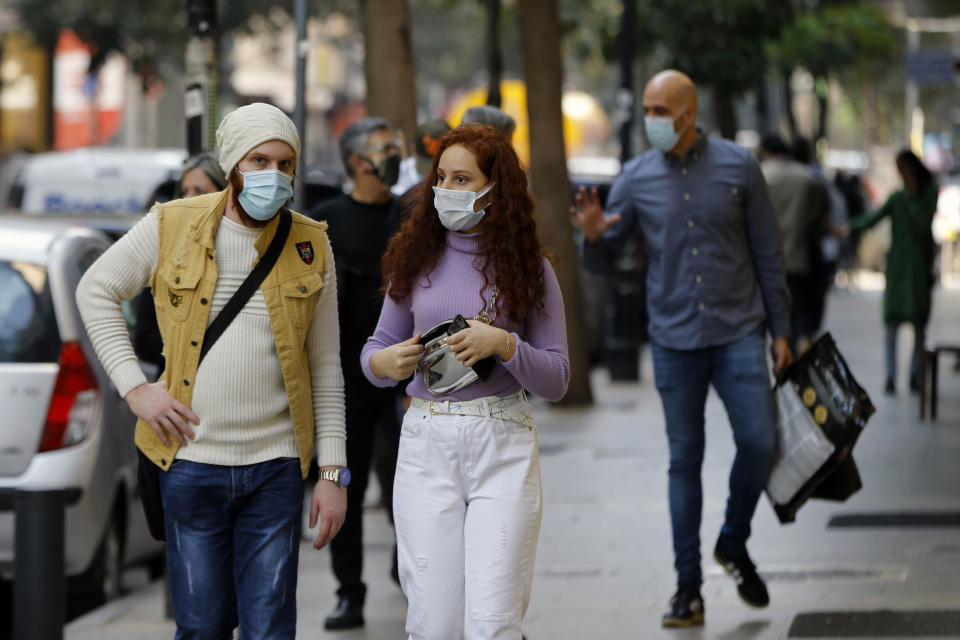 People wear masks to help protect themselves from the coronavirus on Hamra street in Beirut, Lebanon, Monday, Jan. 4, 2021. Lebanon is gearing up for a new nationwide lockdown, as officials vowed Monday to take stricter measures against the coronavirus following the holiday season, which saw a large increase in infections and caused jitters in the country's already-battered health sector. (AP Photo/Bilal Hussein)