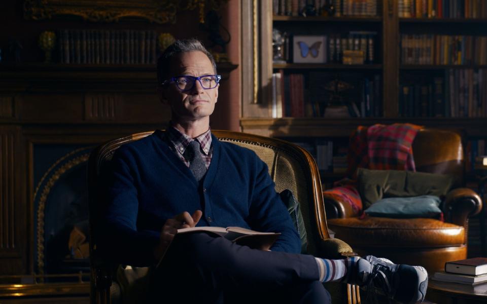 Neil Patrick Harris sitting in a chair with a notebook