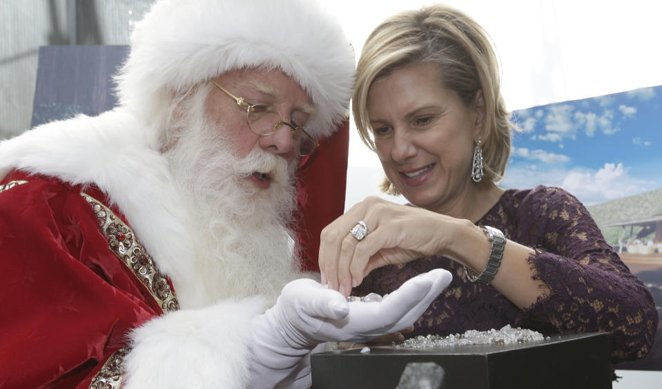 Actor Brady White portrays Santa Claus as jewelry designer Maria Canale hands him loose diamonds offered in the Neiman Marcus Christmas Book Tuesday, Oct. 8, 2013, in Dallas. The Forevermark Ulitmate Diamond Experience on sale for $1,850,000 includes a rough diamond and a trip to London and Africa to trace the provenance of the stone. (AP Photo/LM Otero)