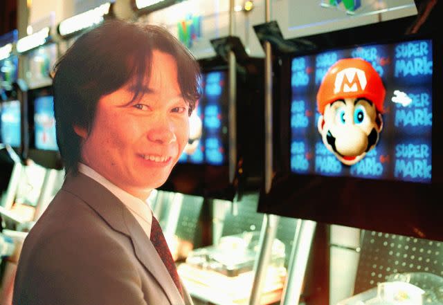 Shigeru Miyamoto in front of a screen displaying with his creation, Mario