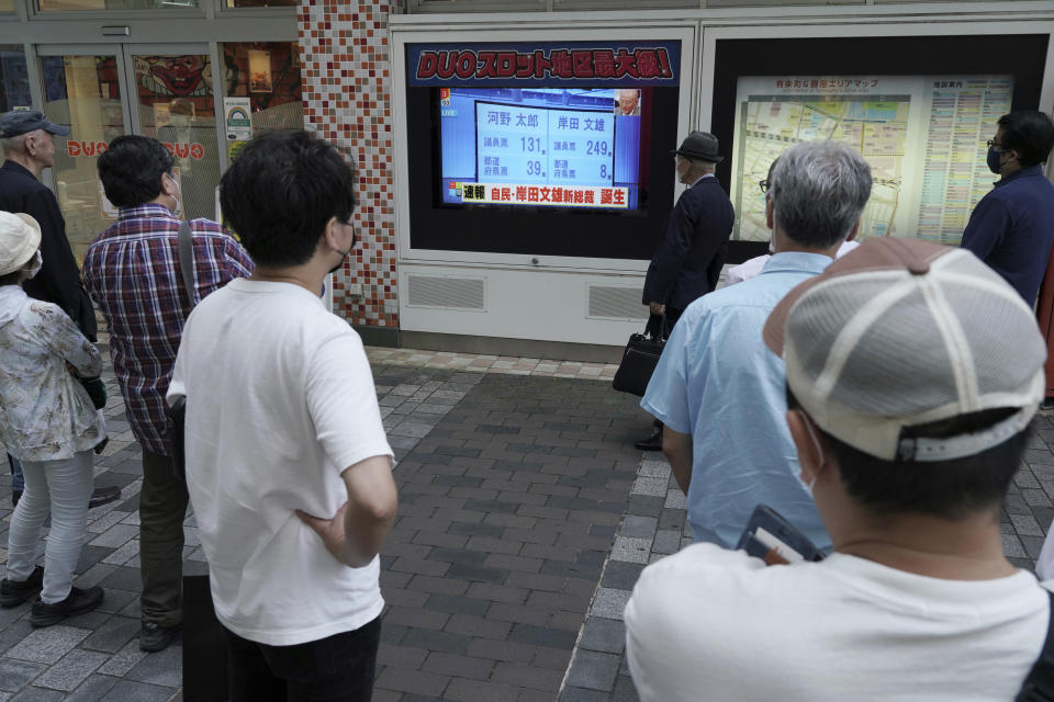 Pedestrians look at a public TV showing the results of the Liberal Democratic Party's presidential election Wednesday, Sept. 29, 2021, in Tokyo. Former Foreign Minister Fumio Kishida has won the governing party leadership election and is set to become the next prime minister. The Japanese letters read: "Fumio Kishida new LDP president." (AP Photo/Eugene Hoshiko)