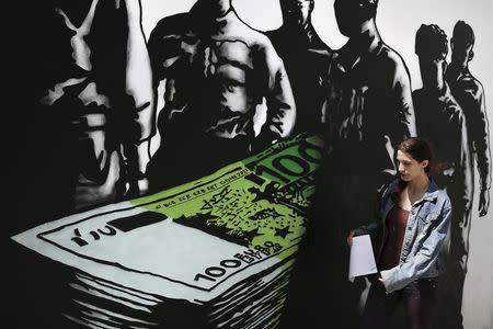 A woman makes her way past a graffiti artwork titled "Death of euros" made by French street artist Goin in Athens May 26, 2015. A senior German official said on Tuesday there was no reason to believe Greece would be in default after a 300 million euro payment to the IMF falls due on June 5. REUTERS/Alkis Konstantinidis