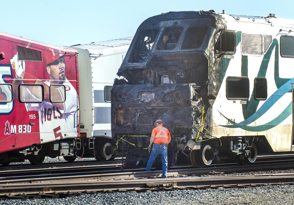 Investigators work at the scene after an RV was hit by a commuter train and burst into flames along a track in Santa Fe Springs, Calif., Friday, Nov. 22, 2019. Authorities say the collision occurred shortly after 5:30 a.m. Friday at an intersection in an industrial area of Santa Fe Springs. There were no immediate reports of injuries. All passengers on the Metrolink train were safely evacuated. (Mark Rightmire/The Orange County Register via AP)