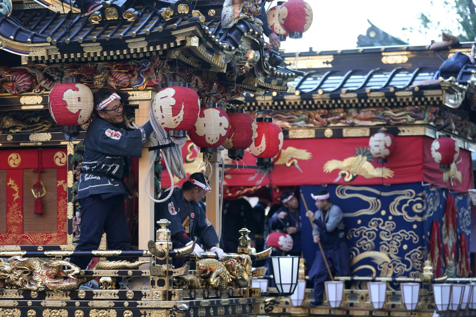 In this Tuesday, Dec. 3, 2019, photo, participants clad in traditional happi coats put lanterns on floats before it goes to the town central square during the Chichibu Night Festival in Chichibu, Japan. Moving six towering floats up a hill and into the town center is the culminating moment of a Shinto festival that has evolved from a harvest thanksgiving into a once-a-year meeting between two local gods. (AP Photo/Toru Hanai)