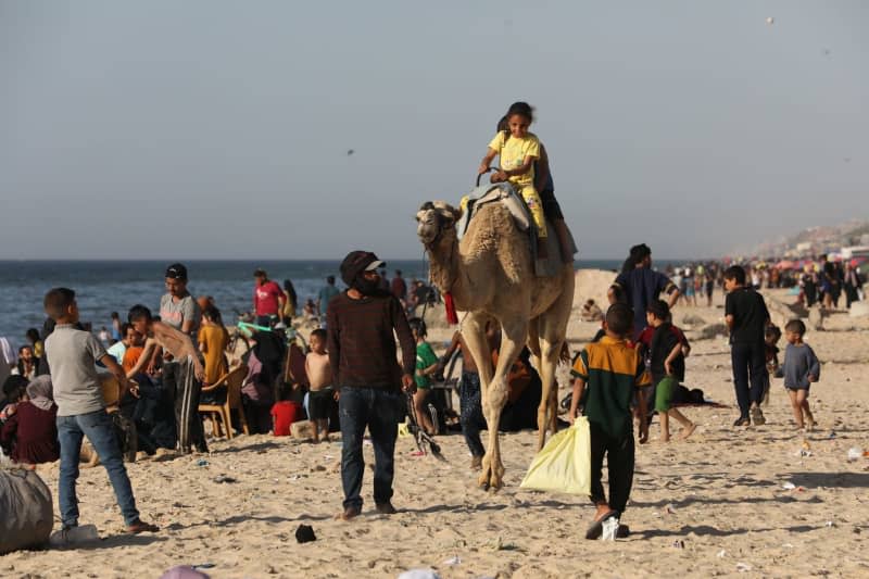 Palestinians gather on the beach of Deir al-Balah while Israeli attacks continue on Gaza. Omar Ashtawy/APA Images via ZUMA Press Wire/dpa