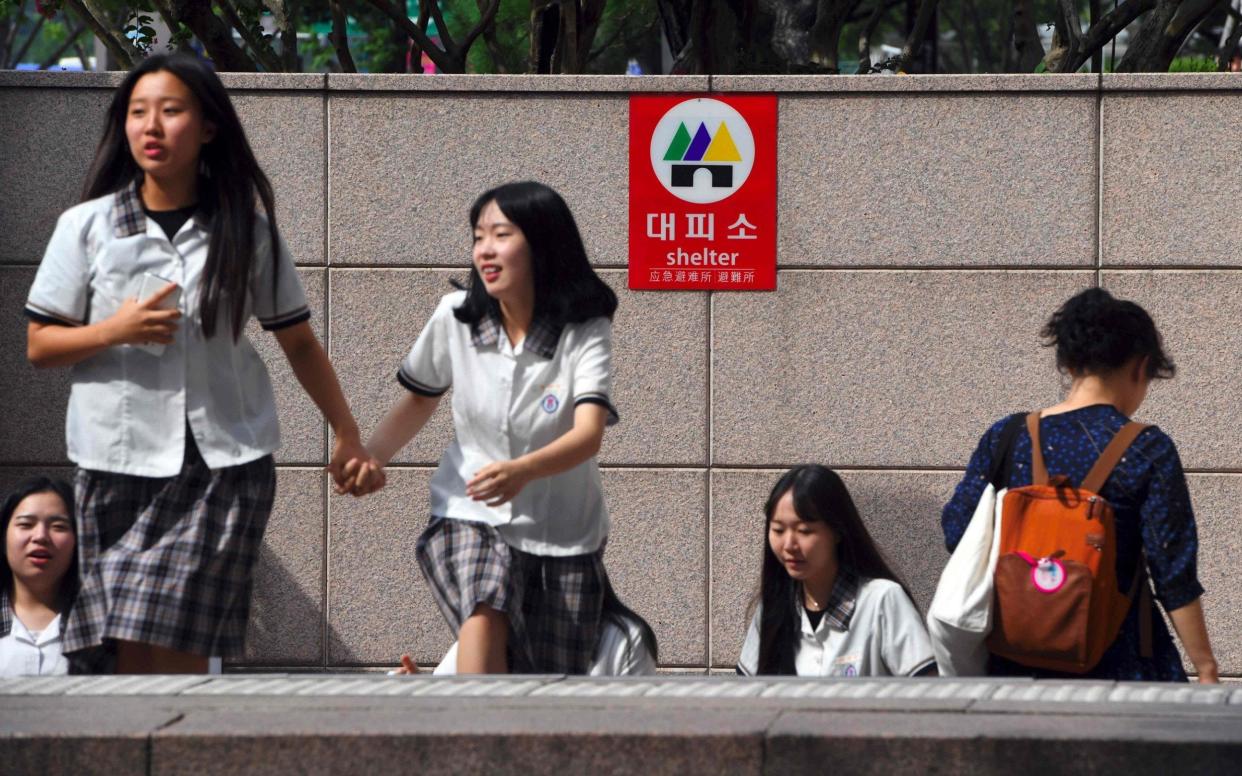 Pedestrians walk past a shelter sign set up on an exit of a subway station in Seoul  - AFP