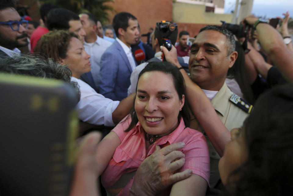 A supporter of National Assembly President Juan Guaido takes a selfie with him speaking in the background after a meeting with residents in the Hatillo municipality of Caracas, Venezuela, Thursday, March 14, 2019. Guaido has declared himself interim president and demands new elections, arguing that President Nicolas Maduro's re-election last year was invalid. (AP Photo/Fernando Llano)