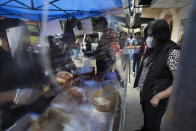 A vendor, wearing a face shield and protective face mask amid the new coronavirus pandemic, prepares a "torta de chilaquiles" for a customer, in Mexico City, Saturday, Aug. 1, 2020. More than half of Mexicans work in the informal economy, which is believed to have shed many more jobs as the economic shutdown caused by the COVID-19 pandemic has driven the country deeper into a recession. (AP Photo/Marco Ugarte)