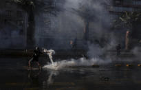 A demonstrator returns a tear gas canister fired by police during a protest against police in reaction to a video that appears to show an officer pushing a youth off a bridge the previous day at a protest, in Santiago, Chile, Saturday, Oct. 3, 2020. (AP Photo/Esteban Felix)