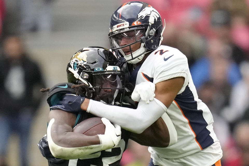 Jacksonville Jaguars running back JaMycal Hasty (22) is tackled by Denver Broncos cornerback Pat Surtain II (2) during the NFL football game between Denver Broncos and Jacksonville Jaguars at Wembley Stadium London, Sunday, Oct. 30, 2022. (AP Photo/Kirsty Wigglesworth)