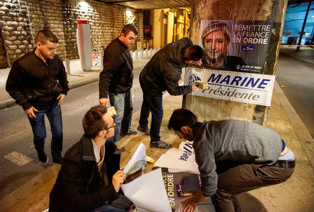 FILE PHOTO: Members of the National Front youths put up posters of Marine Le Pen, French National Front (FN) political party leader and candidate for the French 2017 presidential election, ahead of a 2-day FN political rally to launch the presidential campaign in Lyon, France, February 2, 2017. REUTERS/Robert Pratta/File photo/File Photo