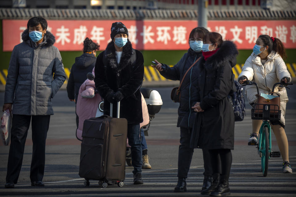 People wearing face masks to protect against the spread of the coronavirus wait to cross an intersection in Beijing, Wednesday, Jan. 20, 2021. China is now dealing with coronavirus outbreaks across its frigid northeast, prompting additional lockdowns and travel bans. (AP Photo/Mark Schiefelbein)