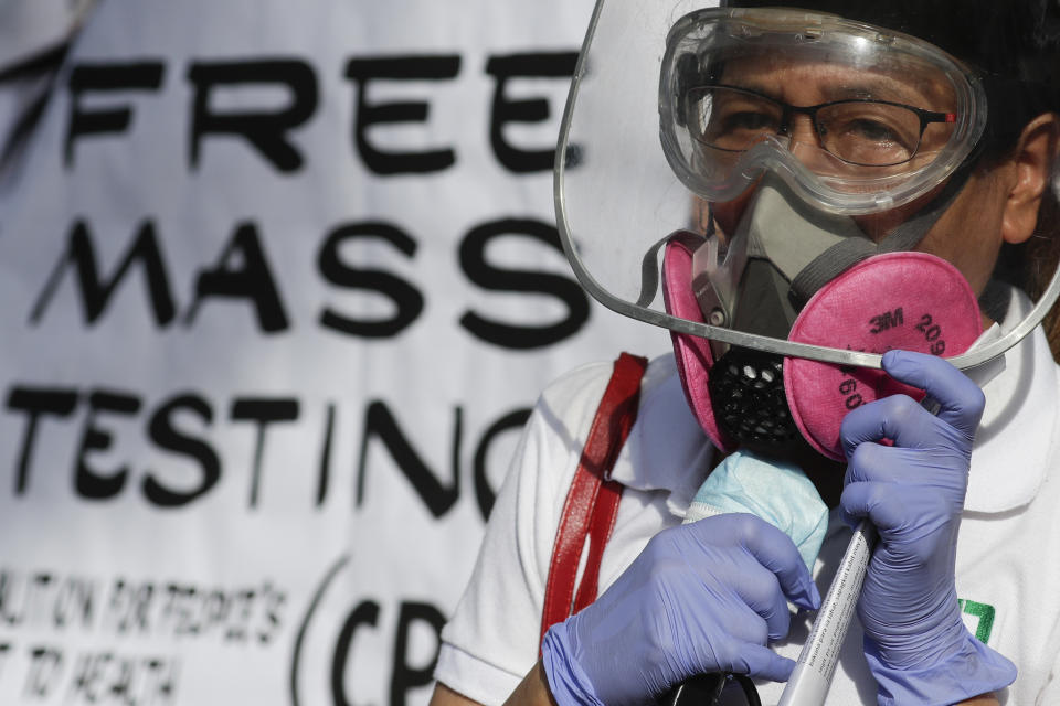 A health worker wearing protective gear talks during a rally at the Philippine Heart Center in Quezon city, Philippines, Friday Jan. 29, 2021. Protesters said that it has been almost one year since the first reported case of the coronavirus in the country and they are still demanding the government for free mass testing, free vaccines and paid quarantine leave for workers. (AP Photo/Aaron Favila)