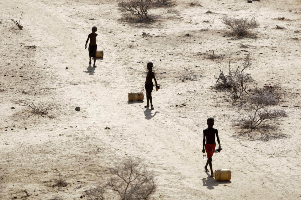Young boys pull containers of water as they return to their huts from a well in the village of Ntabasi village in Samburu East, Kenya, Oct, 14, 2022. Loss and damage is the human side of a contentious issue that will likely dominate climate negotiations in Egypt. (AP Photo/Brian Inganga)