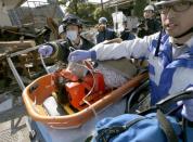 A woman is carried away by rescue workers after being rescued from her collapsed home caused by an earthquake in Mashiki town, Kumamoto prefecture, southern Japan, in this photo taken by Kyodo April 16, 2016. REUTERS/Kyodo