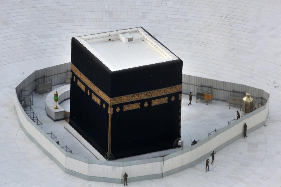 FILE- In this March 6, 2020 file photo, Saudi policemen guard the the Kaaba, the cubic building at the Grand Mosque, in the Muslim holy city of Mecca, Saudi Arabia. The confirmed death toll from the coronavirus has gone over 50,000 in the Middle East as the pandemic continues. That's according to a count Thursday, Sept. 3, 2020, from The Associated Press, based on official numbers offered by health authorities across the region. (AP Photo/Amr Nabil, File)