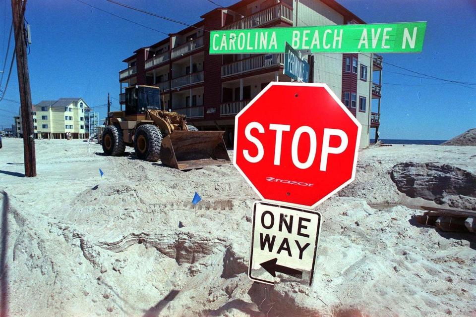 Carolina Beach Ave. North is filled with four feet of sand Friday, Sept. 17, 1999, as work crews use front end loaders to remove the sand left by Hurricane Floyd in Carolina Beach. (AP Photo/Wilmington StarNews, Mark Courtney)