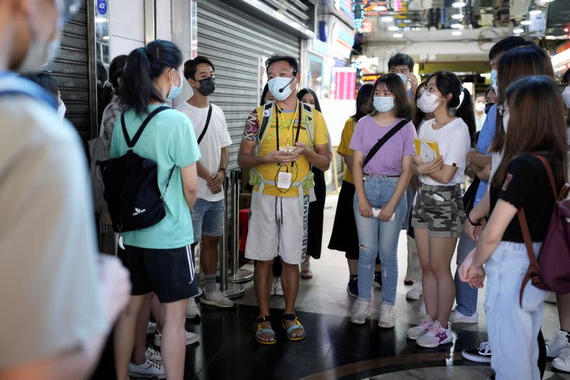Tour guide Michael Tsang speaks to tourists during a tour visiting refugee communities in Hong Kong