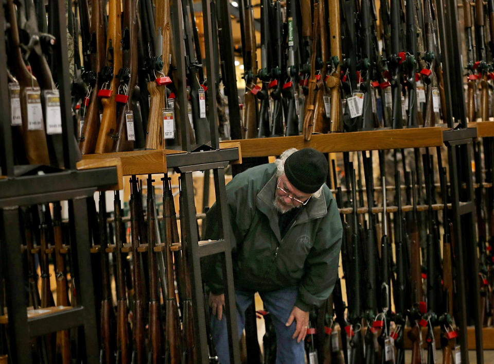 FILE - In this Nov. 29, 2019, file photo, a man looks at the shotgun section of Cabela's while shopping on Black Friday in Hazelwood, Mo. The number of background checks conducted by federal authorities is on pace to break a record by the end of this year. (Christian Gooden/St. Louis Post-Dispatch via AP)