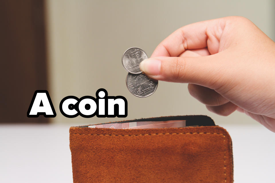 A hand holding two coins above a brown suede wallet with some visible paper currency inside