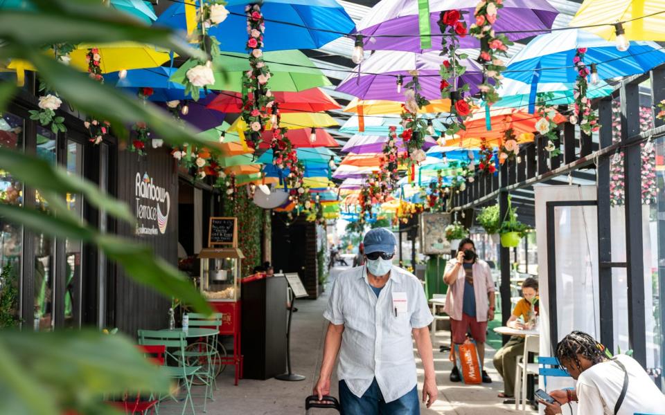 A man wearing a protective mask walks past near the United Palace Theatre in the Washington Heights neighbourhood in Manhattan, New York - Jeenah Moon/Reuters