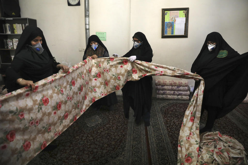 Volunteer women wearing face masks to curb the spread of the new coronavirus prepare fabric to sew bed sheets for hospitals, in a mosque in southern Tehran, Iran, Sunday, April 5, 2020. Iran is battling the worst new coronavirus outbreak in the Mideast. (AP Photo/Vahid Salemi)