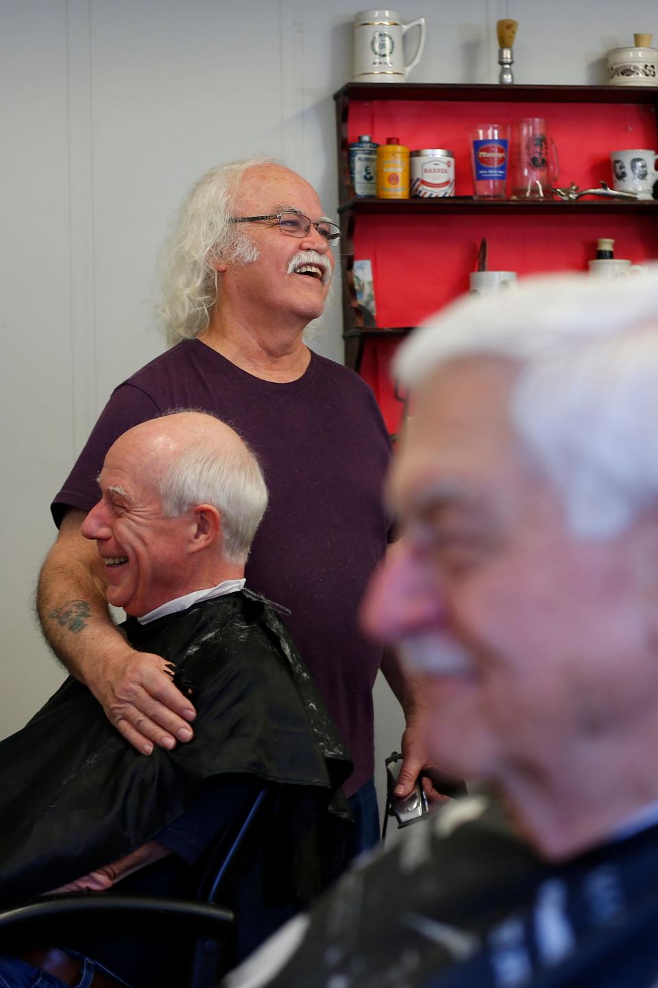 Manny Medeiros enjoys a good laugh with Walter Wallace as he speaks about the forty years he and fellow barber Janice Parker have worked at Not Your Father's Moustache in downtown New Bedford.
