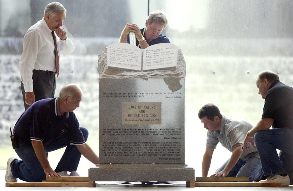 Workmen use a lever to lift the Ten Commandments monument as they prepare to remove it from the rotunda of the Alabama Judicial building on Wednesday morning. Roy Moore supporters have held vigil for a week outside of the judicial building,Mickey Welsh / Advertiser8/27/03