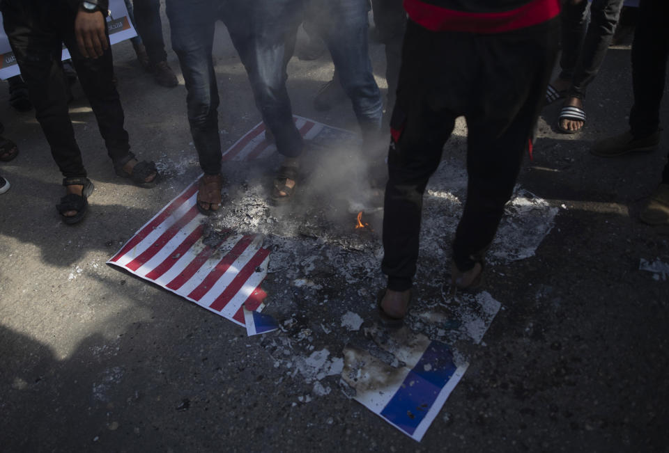 Palestinian protesters step over burning mocks of Israeli and American flags during a protest against the U.S. Mideast peace plan, in Gaza City, Monday, Jan. 28, 2020. U.S. President Donald Trump is set to unveil his administration's much-anticipated Mideast peace plan in the latest U.S. venture to resolve the Israeli-Palestinian conflict. (AP Photo/Khalil Hamra)