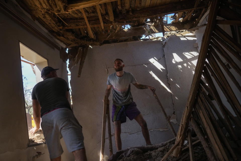 Yaroslav Lazarenko, left, and his cousin Alexei remove debris from his destroyed house after a Russian rocket, hit by Ukraine's anti-aircraft system, stroke in a residencial area in Zaporizhzhia, Ukraine, Thursday, April 28, 2022. The strike came as parts of southern Ukraine prepare for a further advance by Russian forces who seek to strip the country of its seacoast. (AP Photo/Francisco Seco)