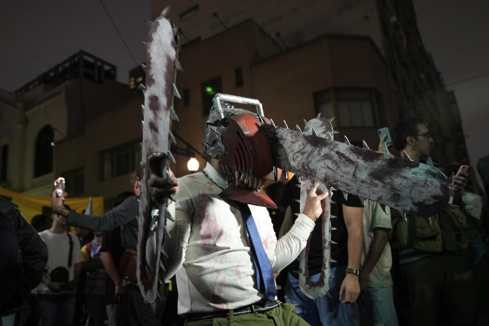 A supporter of presidential candidate Javier Milei wears a chain saw mask outside his campaign headquarters after polls closed for general elections in Buenos Aires, Argentina, Sunday, Oct. 22, 2023. (AP Photo/Mario De Fina)